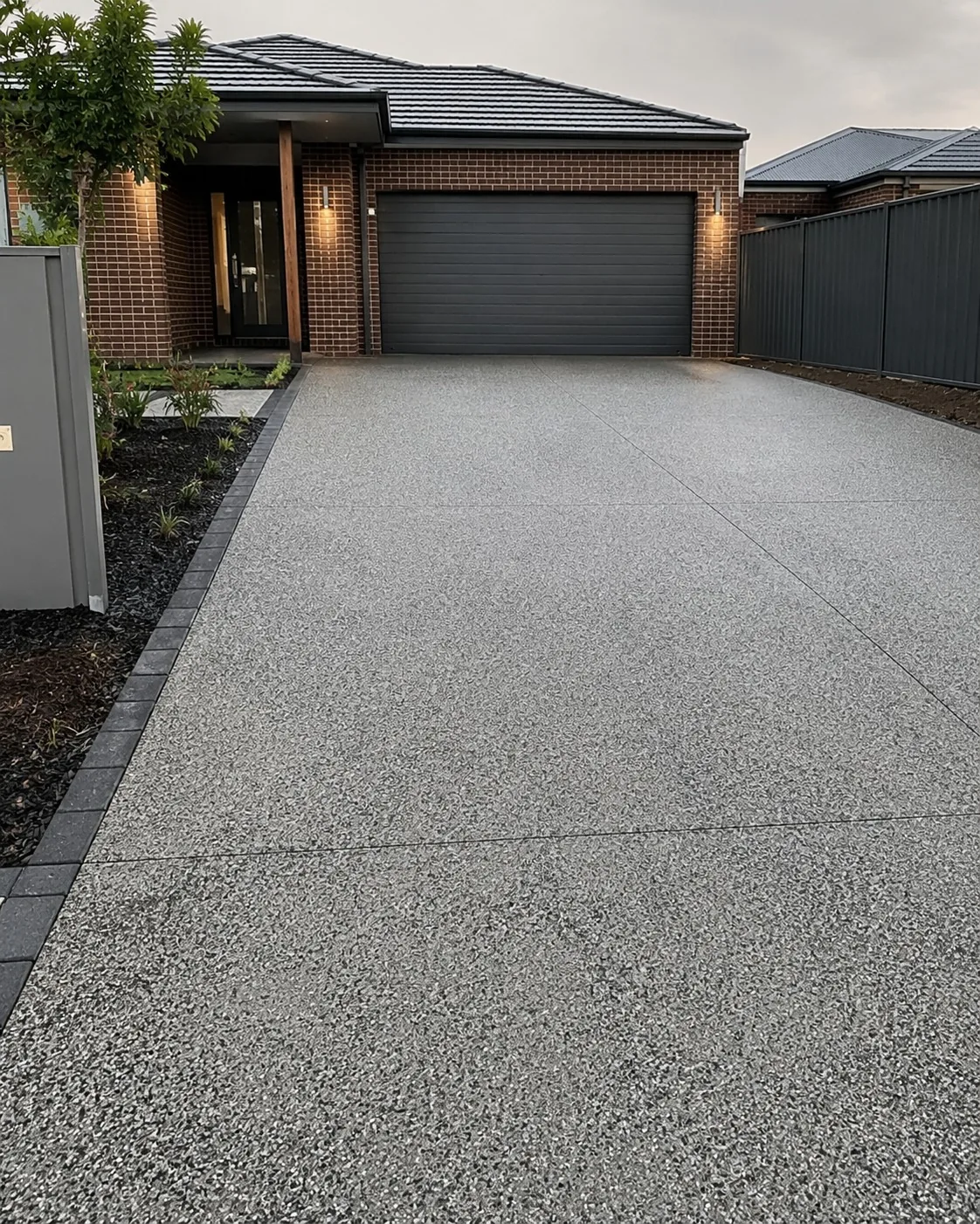 Salt and pepper exposed aggregate driveway with charcoal paver edging at a Melbourne home